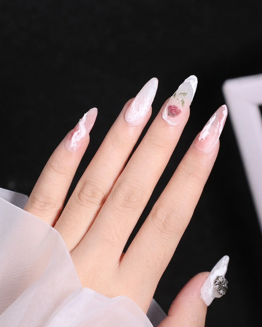 Nahaufnahme eines Fineliner-Pinsels, der weiße Gel-Umrisse der oberen Blütenblätter einer Rose auf einen Fingernagel aufträgt.