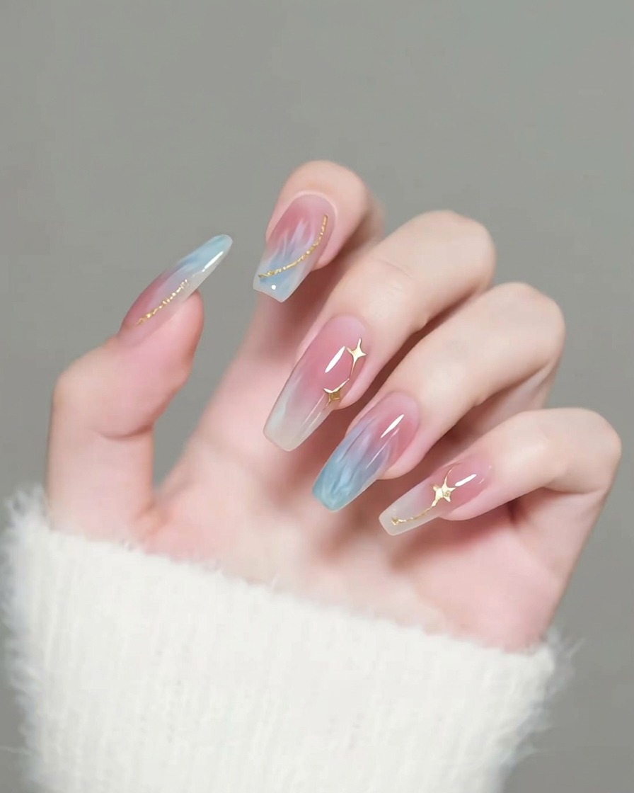 Ein Pinsel trägt einen klaren, glänzenden Top Coat auf Nägel auf, die mit goldenen Sternverzierungen dekoriert sind.