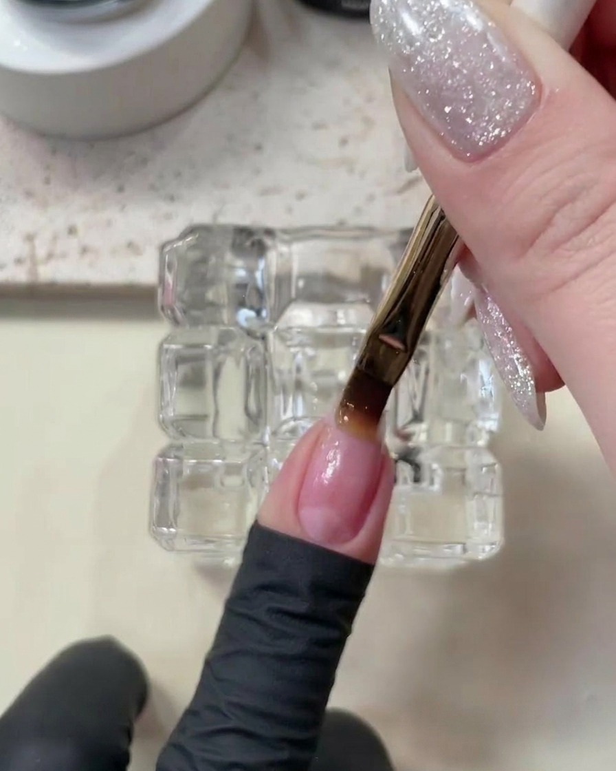 Eine Hand liegt in einer weißen UV/LED-Nagellampe, während der Base Coat auf den Nägeln aushärtet.