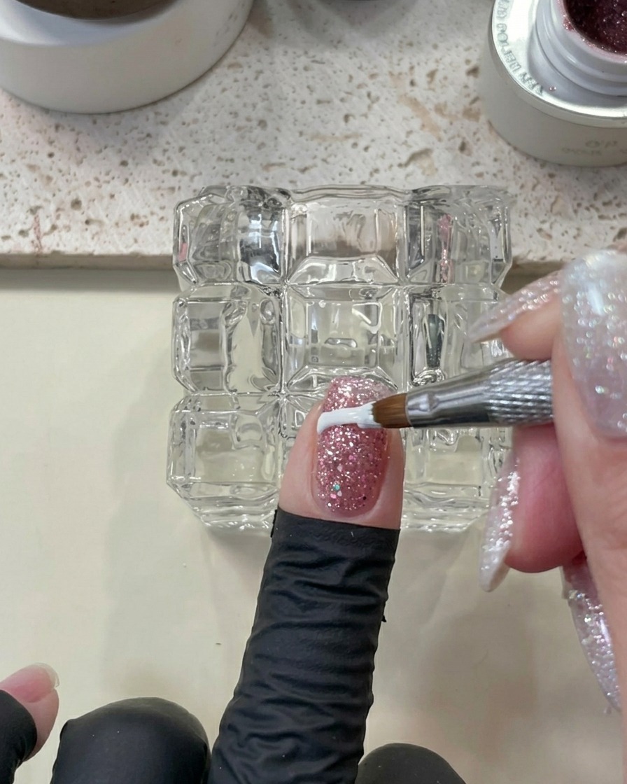Nahaufnahme eines Fingers mit Glitzergel, der mit einem Werkzeug gesäubert wird und für den Aushärtungsprozess bereit ist.