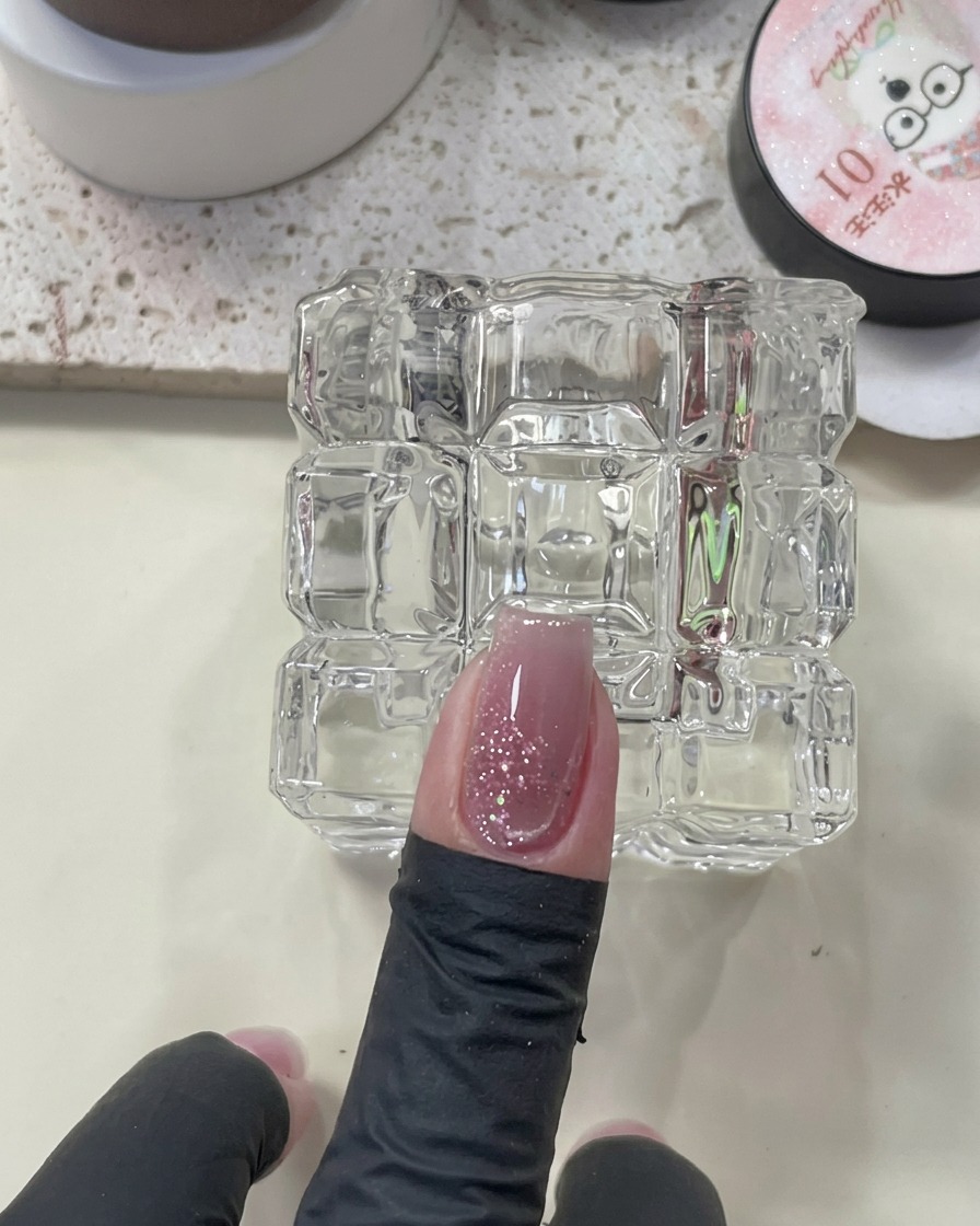Ein Magnetwerkzeug ist über einem Nagel mit feuchtem Cat-Eye-Lack positioniert, um einen leuchtenden Streifen zu erzeugen.