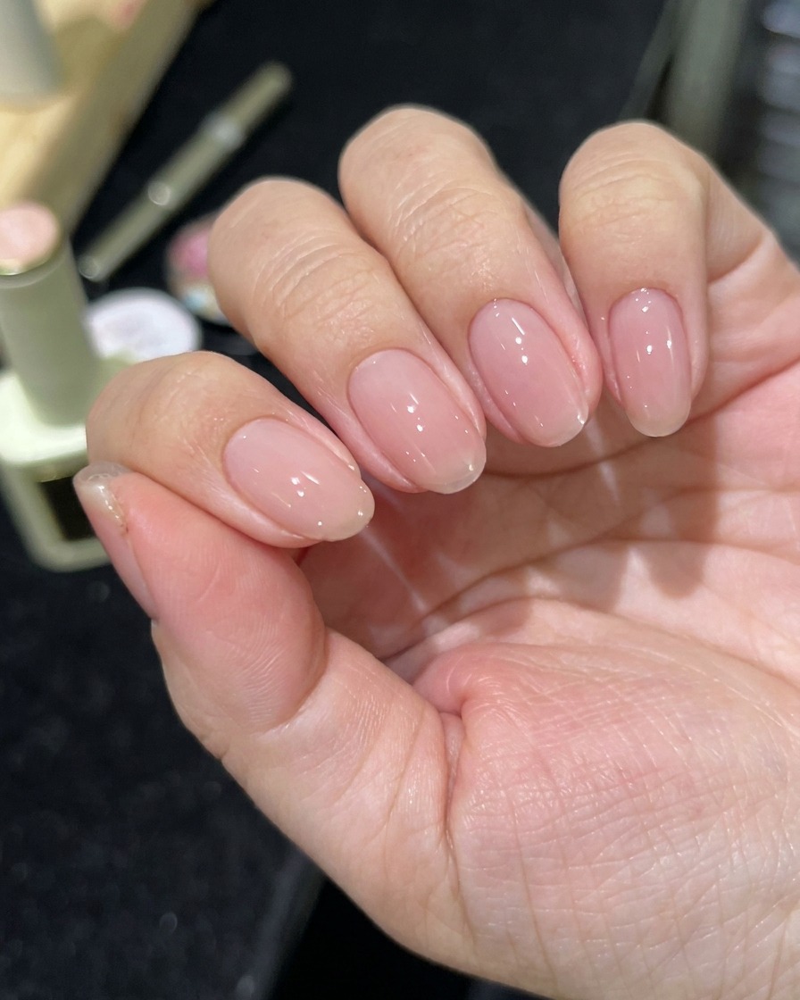 Eine Hand in einer professionellen LED-Nagellampe beim Aushärten der Nägel.
