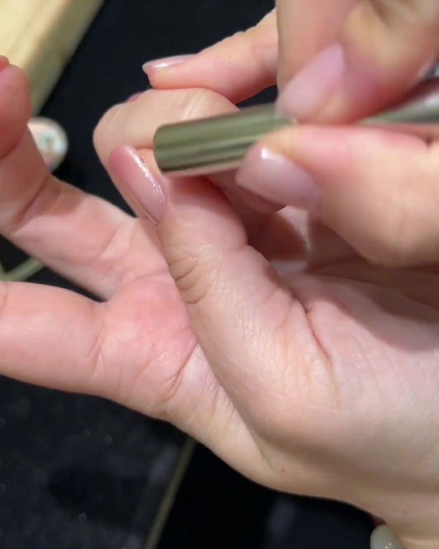 Ein Magnetstab wird über einen mit Cat-Eye-Gel beschichteten Nagel gehalten, wobei sich das Pigment verschiebt, um einen Magneteffekt zu erzeugen.