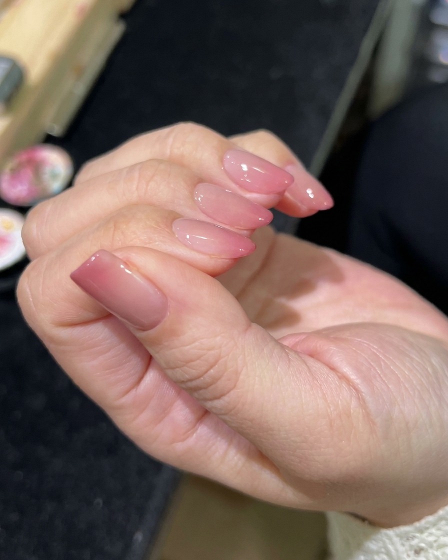 Ein Pinsel trägt einen klaren, glänzenden Überlack auf die fertige magnetische Nail Art auf.