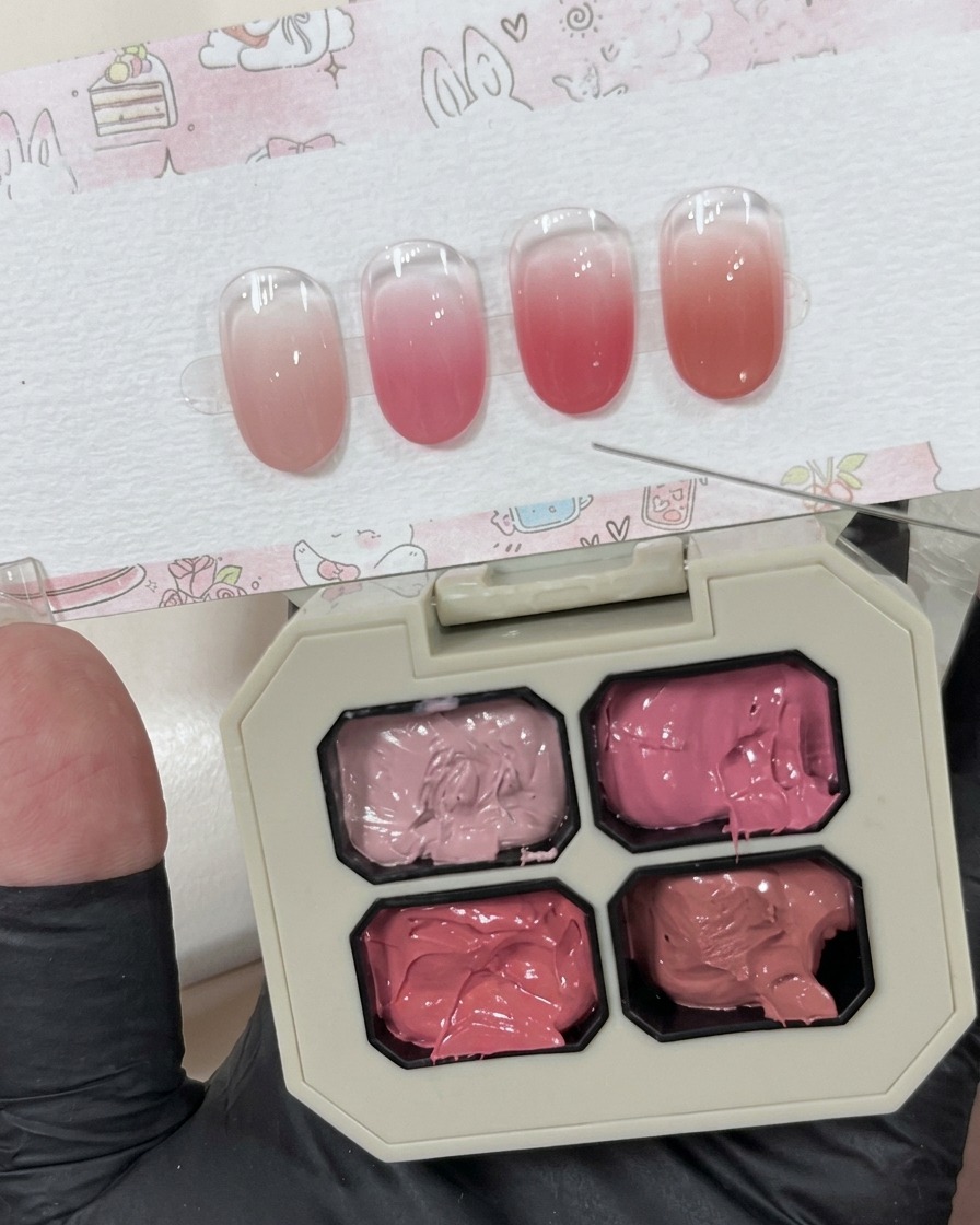 Eine kleine Menge cremiges rosa Gel, das neben der Hauptpalette auf einer weißen Oberfläche liegt.