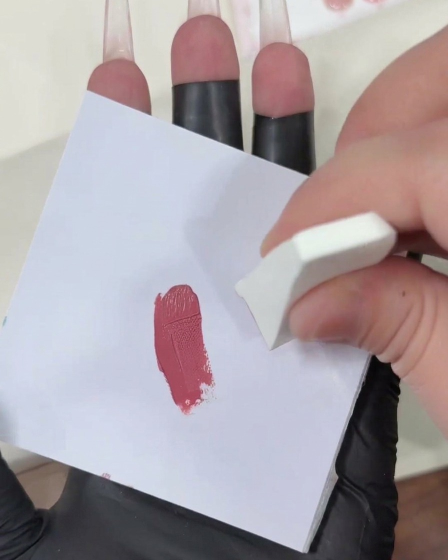 Tupfen eines mit Gel beladenen Make-up-Schwamms auf eine saubere weiße Oberfläche, um die Pink-Farbe zu verblenden.
