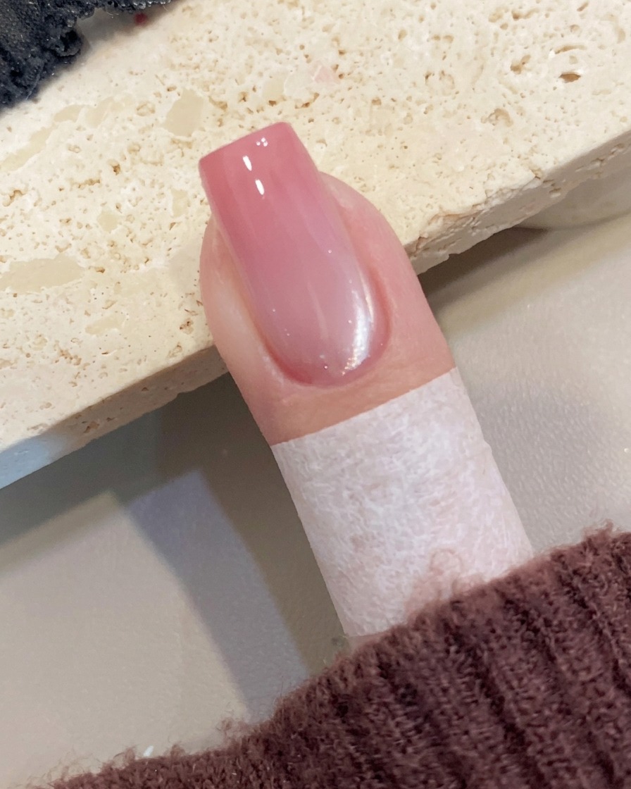Nahaufnahme einer Hand, die vorsichtig ein Schutzband von der Haut um den Nagel entfernt.