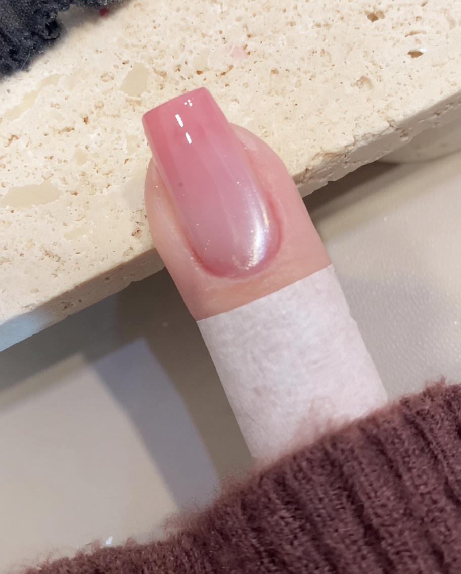 Nahaufnahme, wie ein Pinsel transparentes, schimmerndes Cat-Eye-Gel auf einen vorbereiteten Nagel aufträgt.