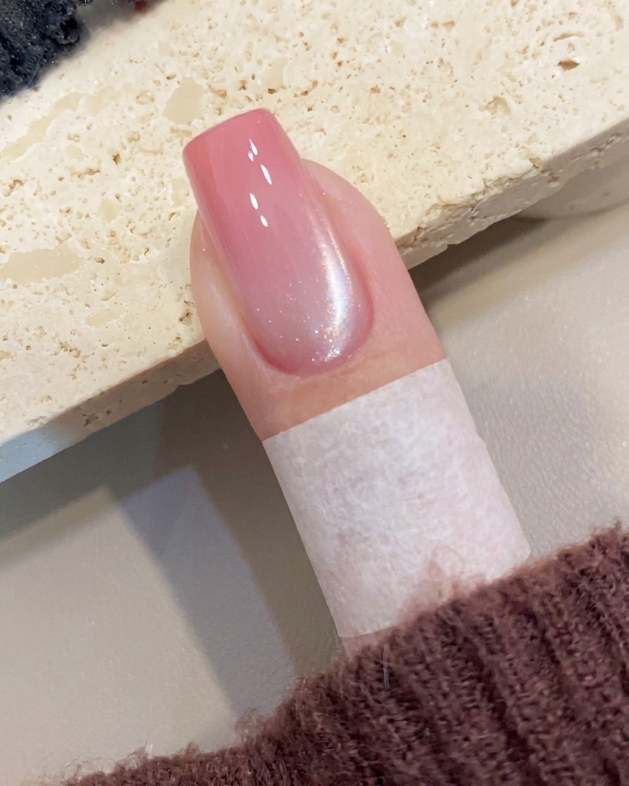 Ein Magnetwerkzeug wird nah an die Seite eines Nagels gehalten, um einen diagonalen Schimmer im feuchten Cat-Eye-Gel zu erzeugen.