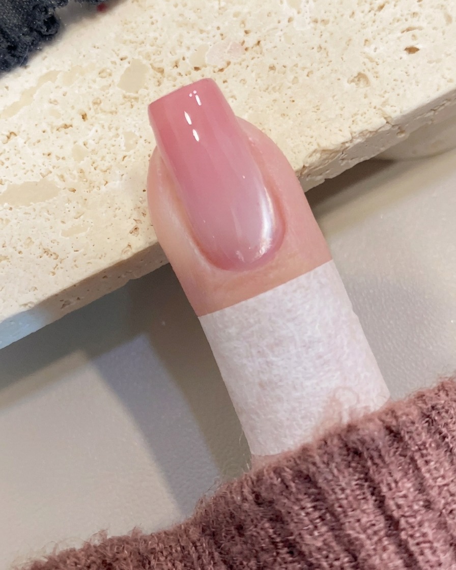Eine kleine Menge pfirsichfarbenes Gel wird mit einem Pinsel auf die freie Nagelspitze platziert.
