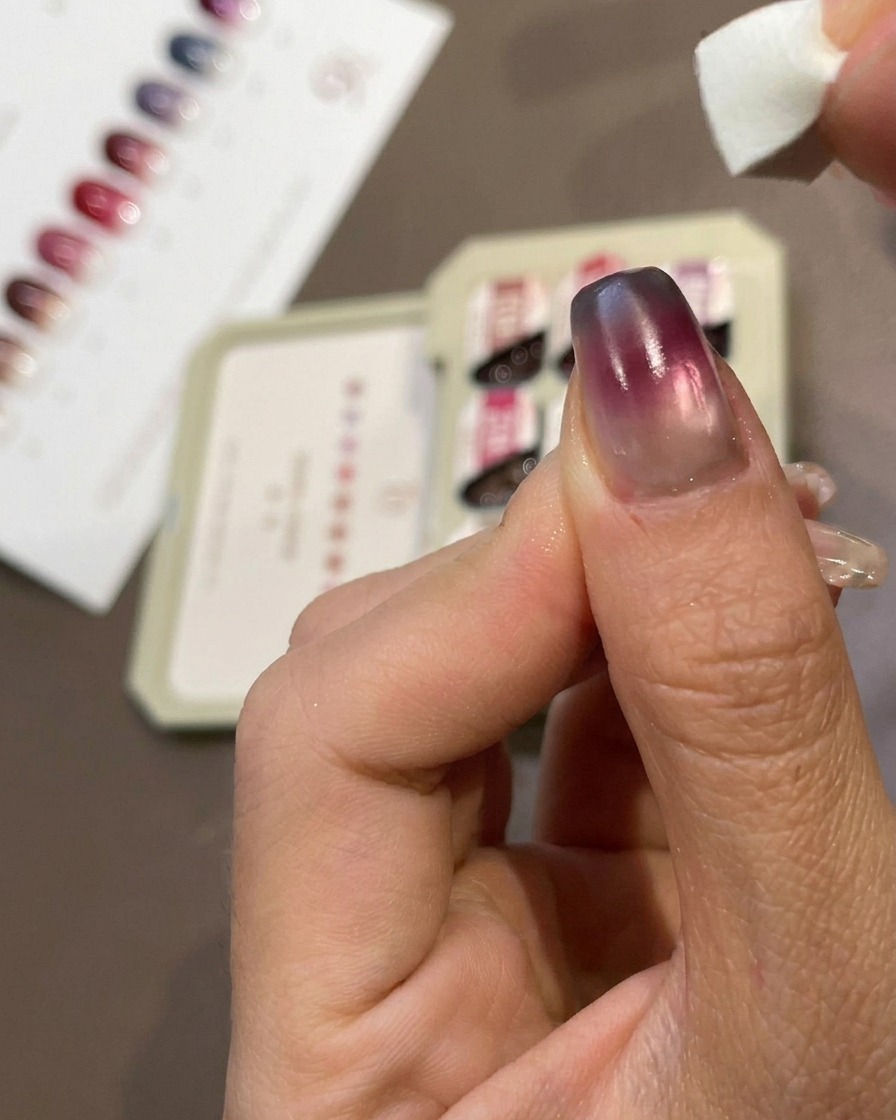 Nahaufnahme eines Fingers, wie ein kleiner Make-up-Schwamm blaues Gel auf die Spitze eines manikürten Nagels tupft.