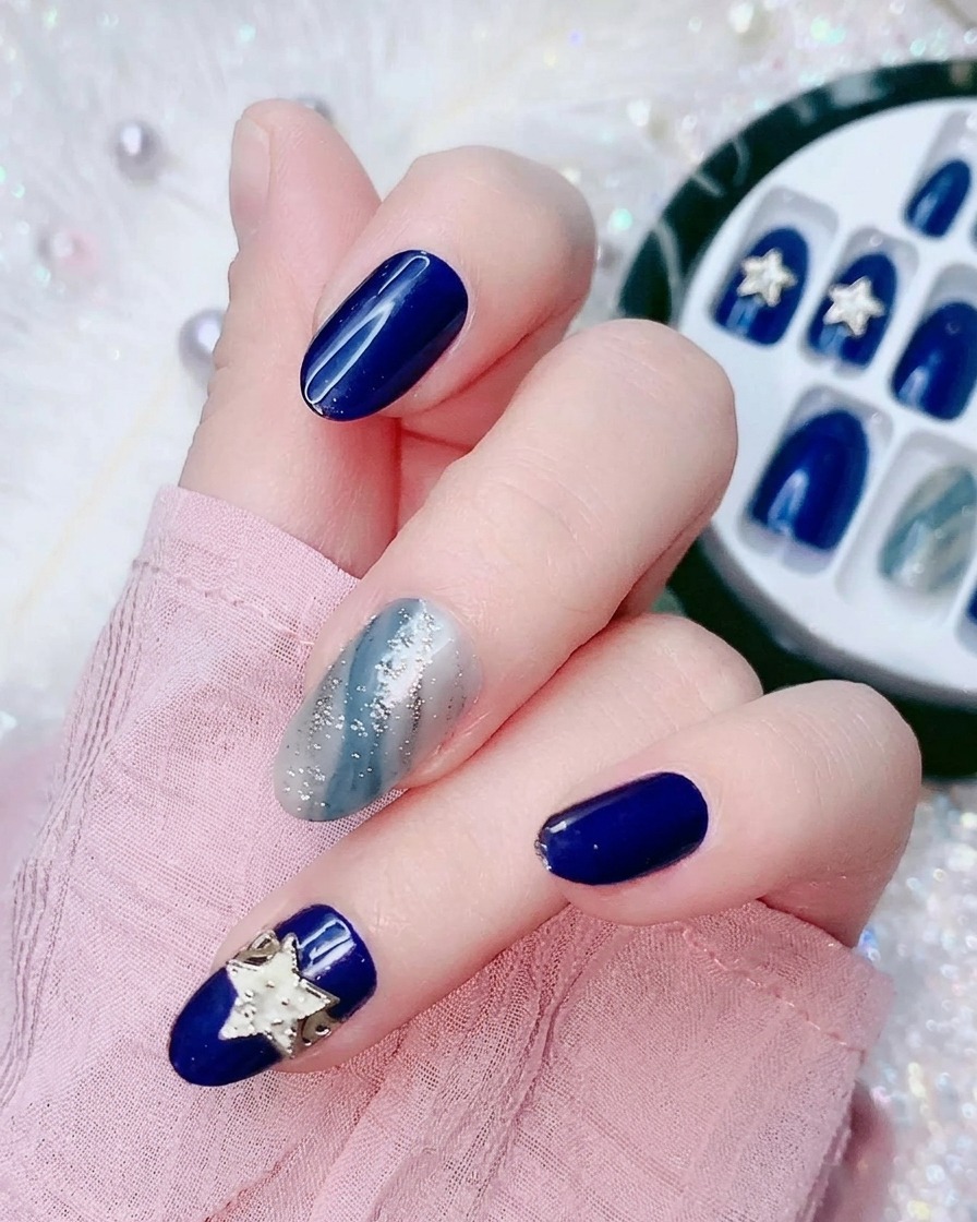 Nahaufnahme eines Fingers, der eine kleine durchsichtige Plastikfolie von der Rückseite eines elektrisch blauen Press-On Nagels abzieht.