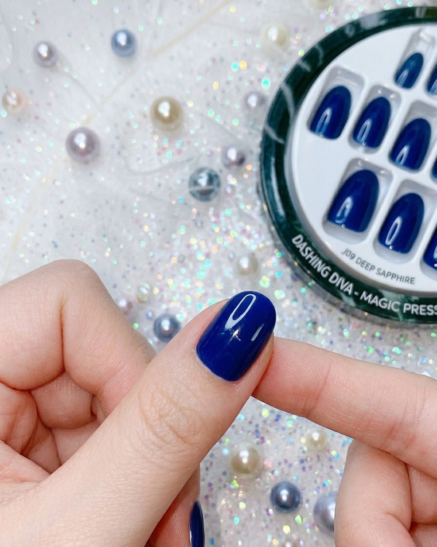 Nahaufnahme eines Fingers, der Druck auf einen tiefblauen Press-On Nagel ausübt, um die Haftung zu finalisieren.