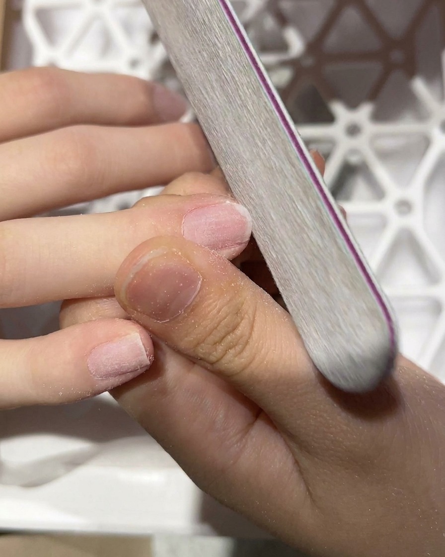 Nahaufnahme einer Handfeile, die die Oberfläche eines Naturnagels mattiert.