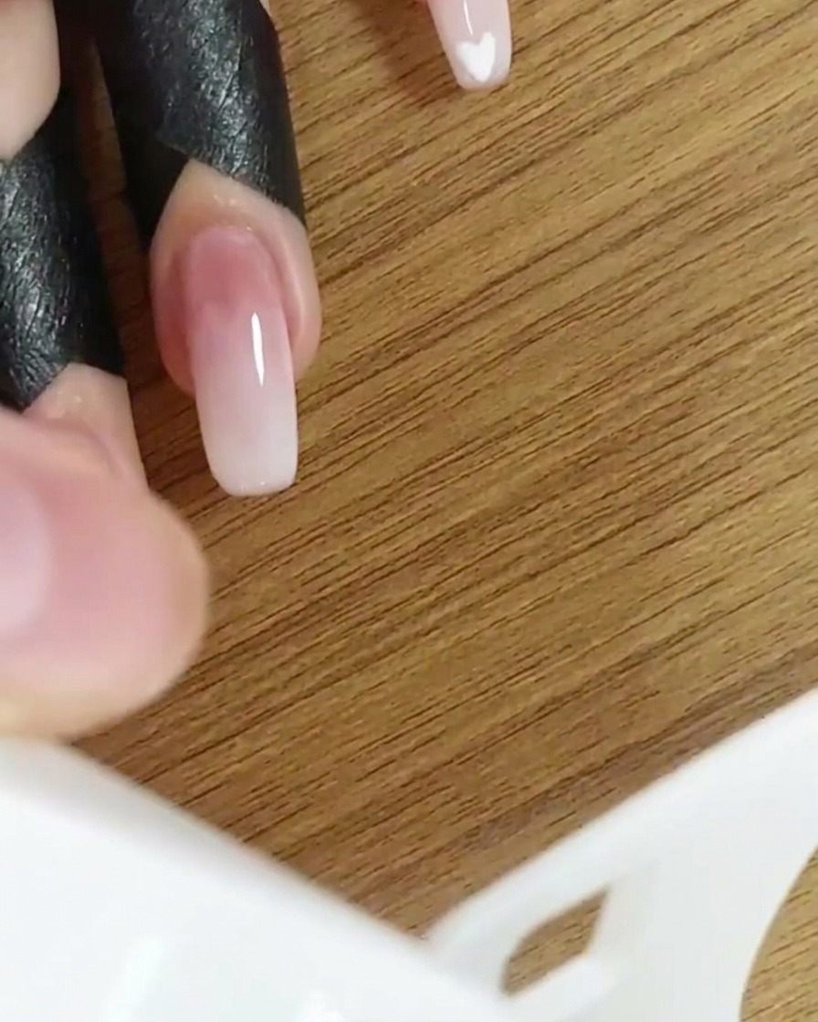 Eine Hand in einer UV/LED-Nagellampe härtet das Ombré-Design aus.