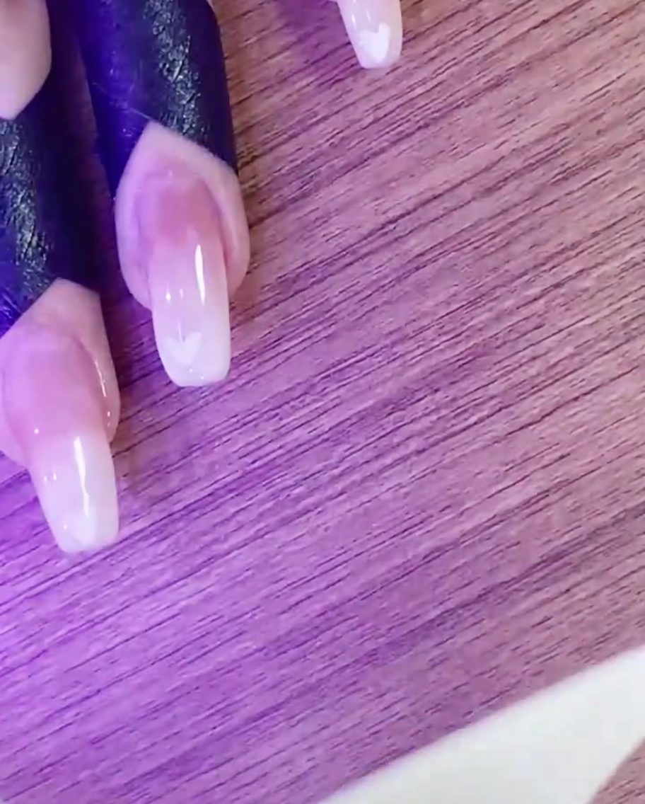 Eine Hand härtet das Herz-Design unter einer UV/LED-Lampe aus.