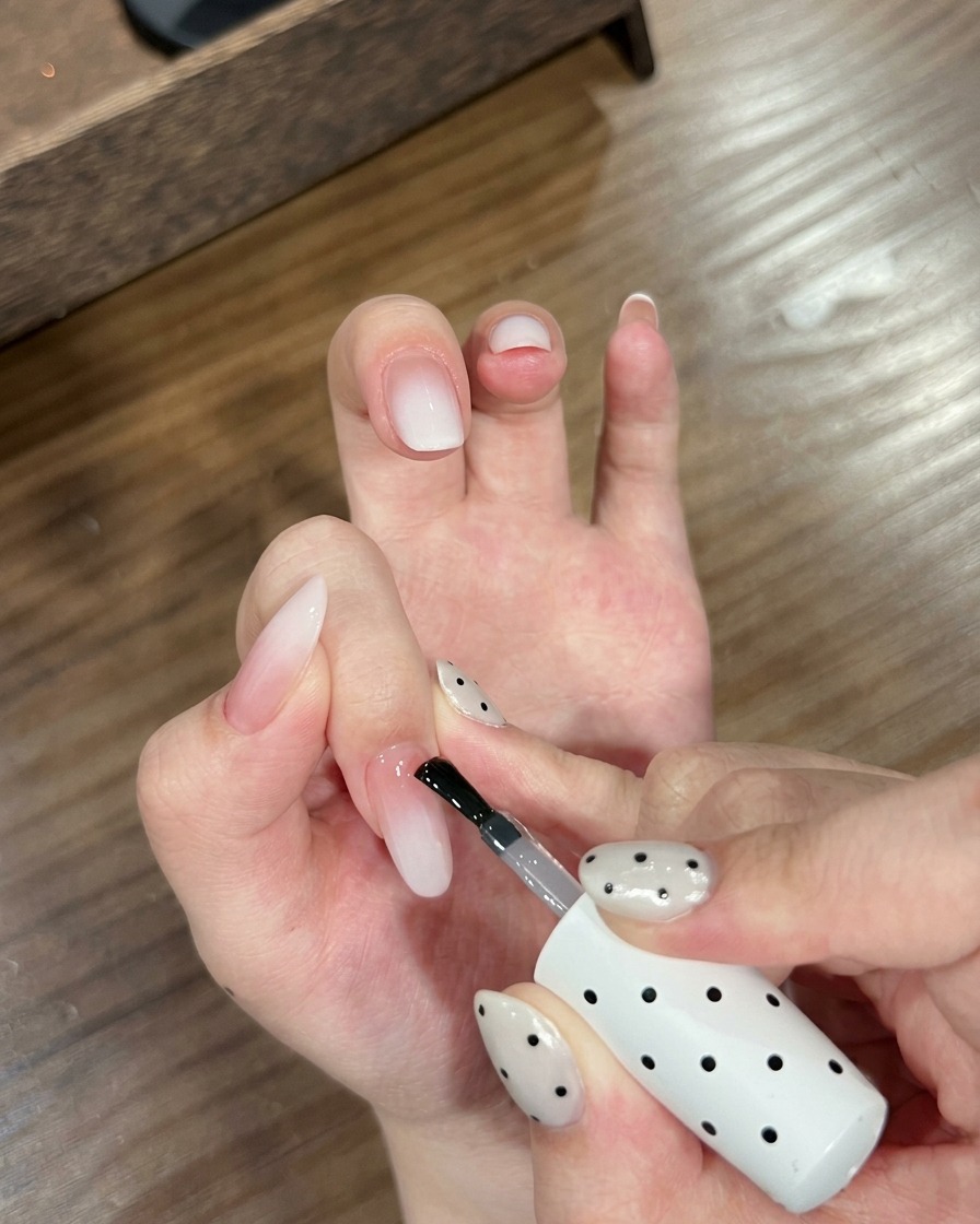 Nahaufnahme einer Hand mit Ombré-Nägeln, die in einer UV-Nagellampe positioniert ist.