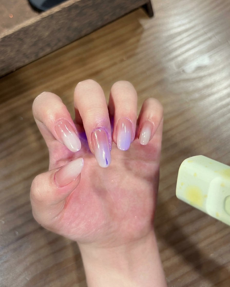 Eine Hand mit Ombré-Chrome-Nägeln in einer UV/LED-Lampe zum Aushärten.