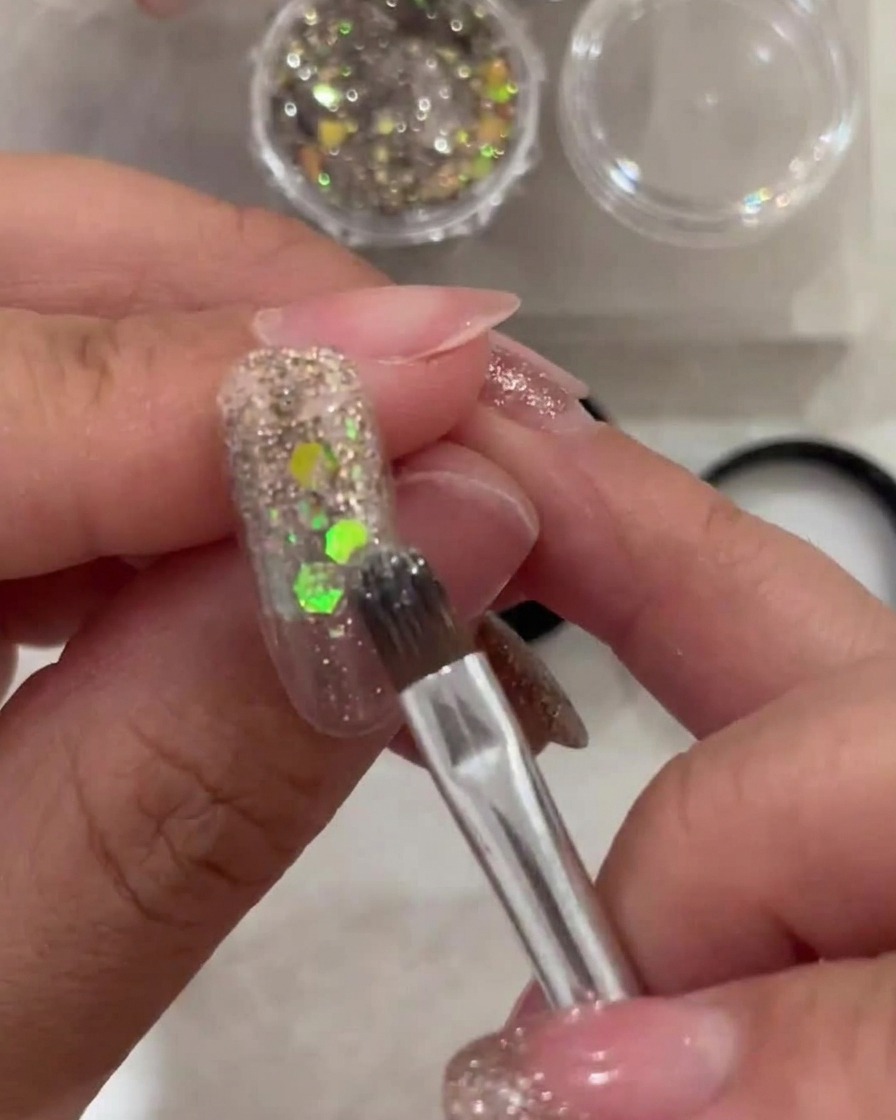 Ein Pinsel trägt eine dünne Schicht transparentes weißes Gel auf die Nagelspitze auf und verblendet Richtung Ansatz.