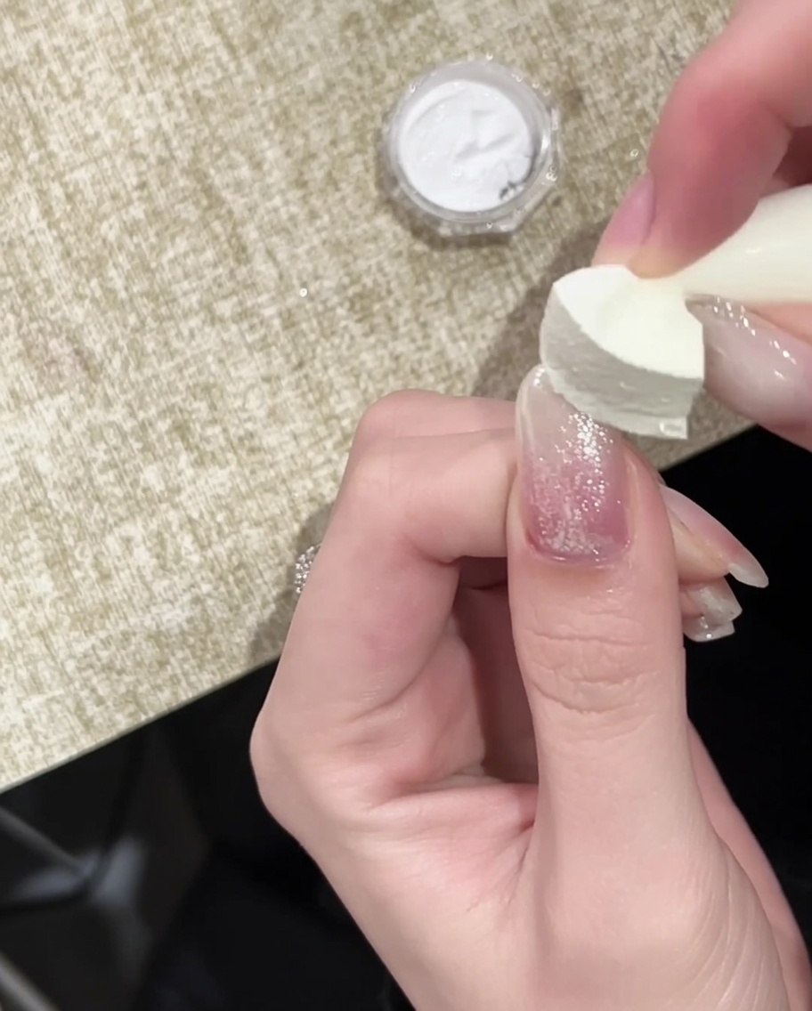 Ein Pinsel trägt einen finalen glänzenden Top Coat über den mit Gold Chrome verzierten Nagel auf.