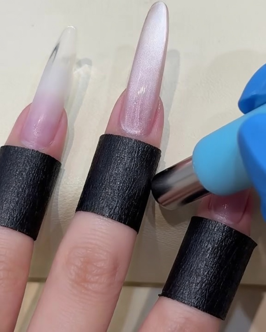 Ein zylindrischer Magnet wird nahe an einen frisch lackierten Nagel gehalten, um die magnetischen Partikel zu verschieben.