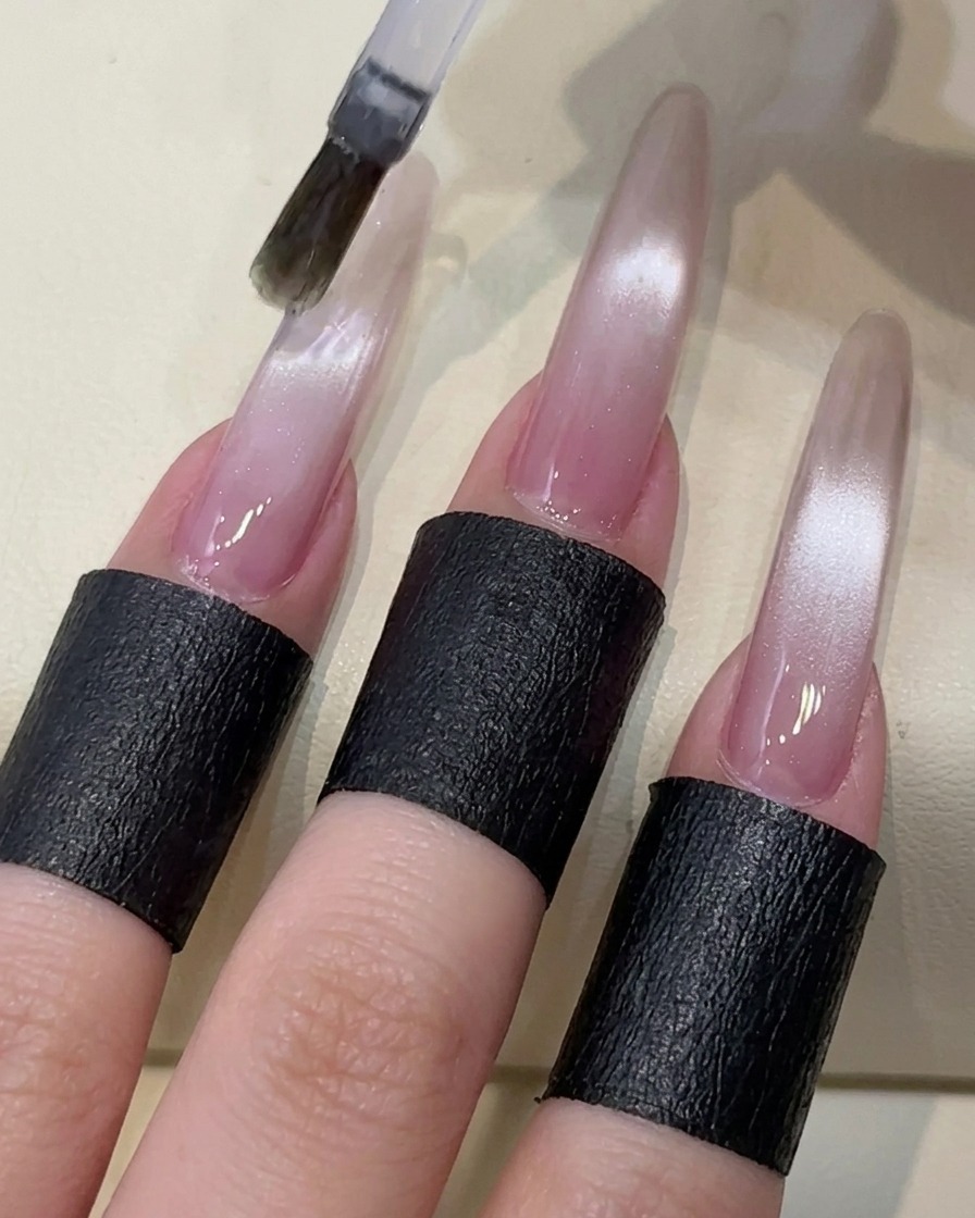 Ein Pinsel trägt einen klaren, nicht klebenden Top-Coat über den Cat-Eye-Nagel auf.