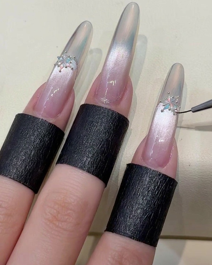 Ein Pinsel trägt einen letzten, festen Top-Coat auf, um die Kanten des Nagels und die dekorativen Kristalle zu versiegeln.