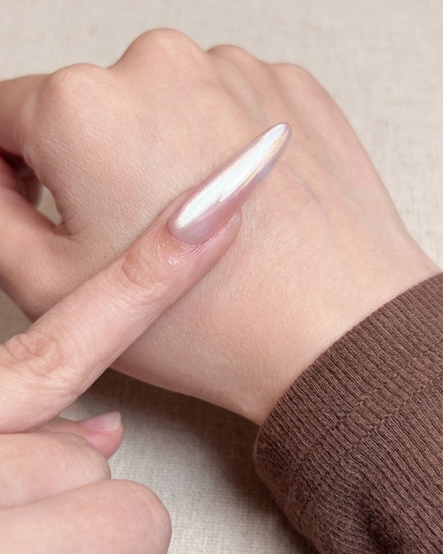Nahaufnahme eines Pinsels, der eine zweite Schicht Nude-Gel-Lack über die Basisschicht aufträgt, wodurch ein deckendes und glattes Finish entsteht.