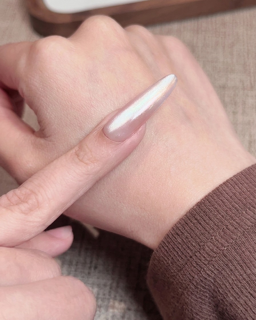 Ein Nagelpinsel trägt einen transparenten rosa Top Coat über einen Nagel mit Blush-Verlauf auf.