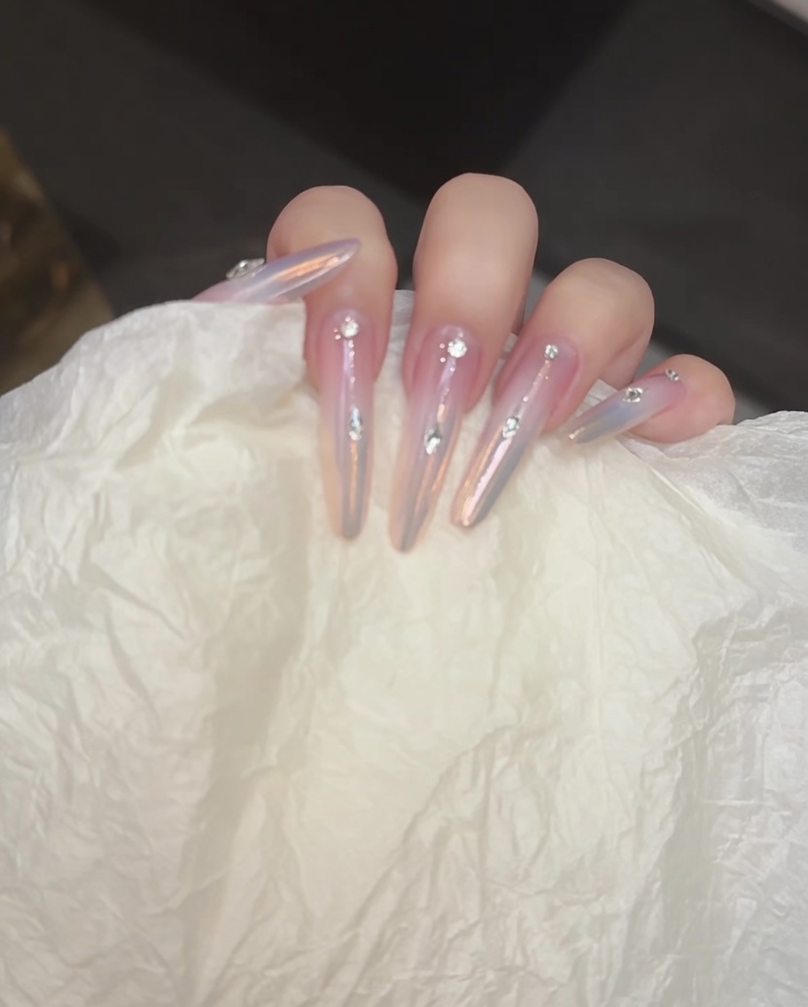 Ein feiner Detailpinsel malt eine gerade silberne Linie über die Nagelmitte.
