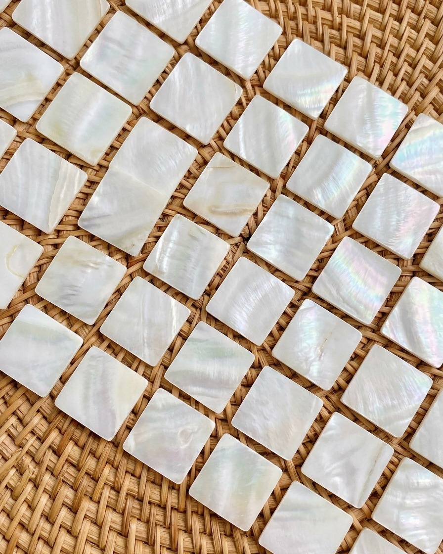 Nahaufnahme von kleinen, irisierenden Opal-Flocken, die mit einer Pinzette auf einen Nageltipp gesetzt werden.