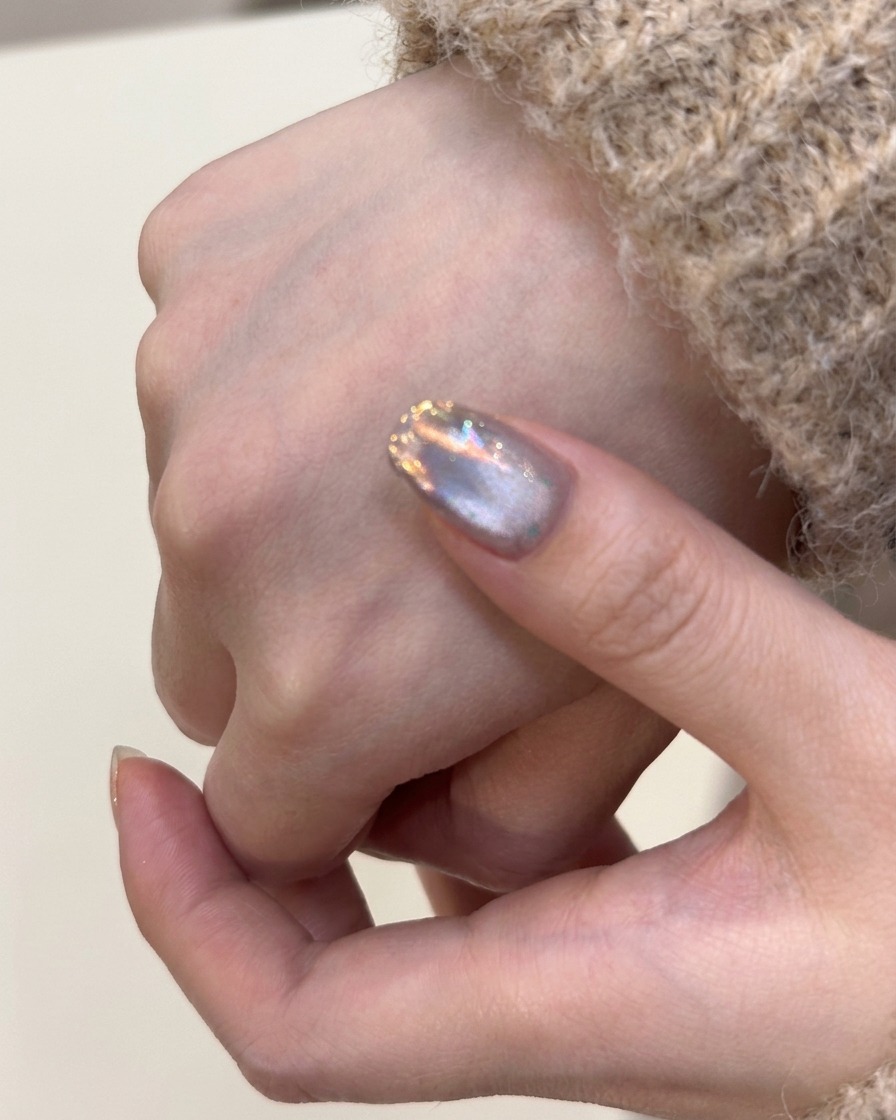 Ein Pinsel trägt eine Schicht silbernes Cat-Eye-Gel auf einen Naturnagel auf.