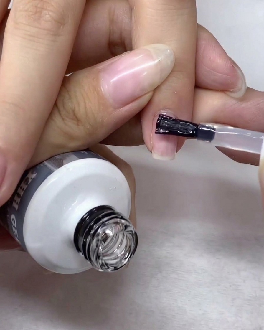 Ein Nagelkunstpinsel verteilt vorsichtig klares Aufbau-Gel über die gesamte Nageloberfläche.