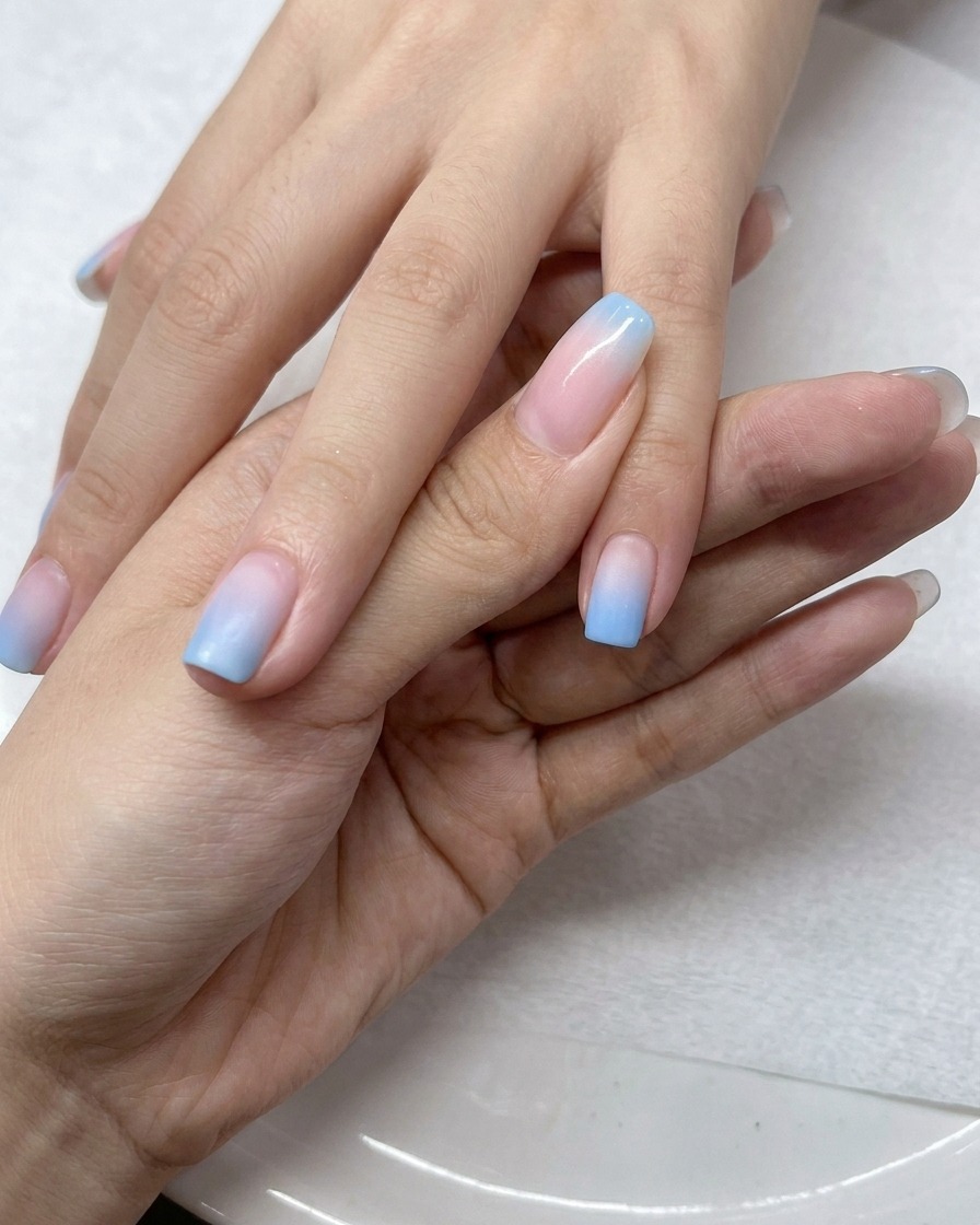 Ein Pinsel trägt eine Schicht klaren Top Coat über den Ombré-Nägeln auf.