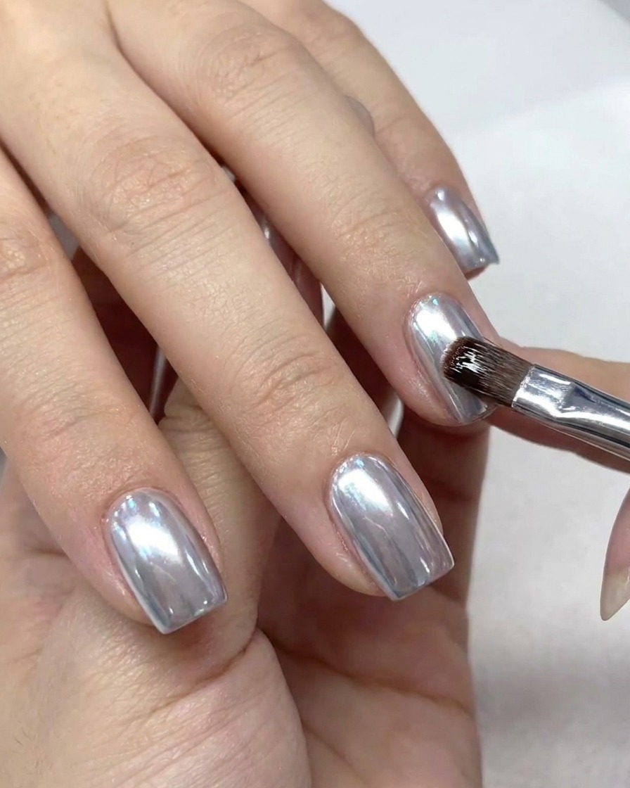 Ein kleiner Make-up-Pinsel entfernt überschüssiges Puder von der Nagelhaut.