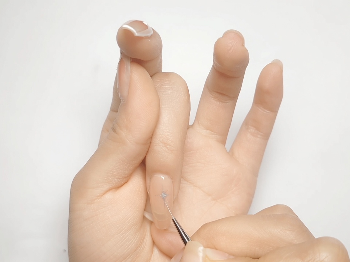 Ein Pinsel füllt die diamantförmigen Ecken eines silbernen Sterns auf einem Nude-Nagel aus.