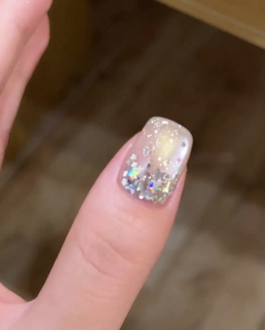 Nahaufnahme, wie ein Pinsel eine dünne Schicht weißes Gel auf die Nagelspitze aufträgt.