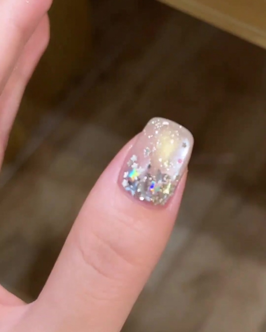 Ein Nagel mit einer Mischung aus großen und kleinen sternförmigen Pailletten auf der Nagelplatte.