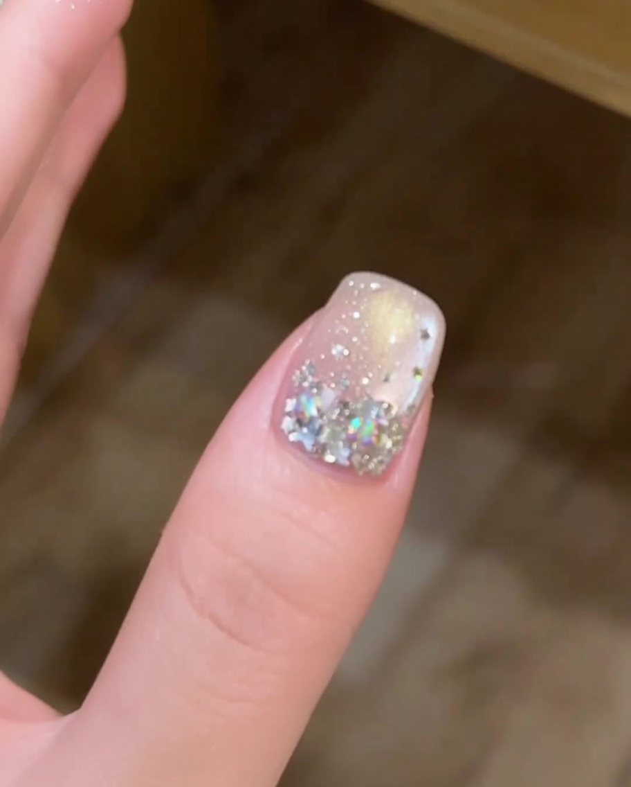Eine Hand in einer professionellen Nagellampe, wobei der dekorierte Fingernagel deutlich unter dem UV-Licht zu sehen ist.