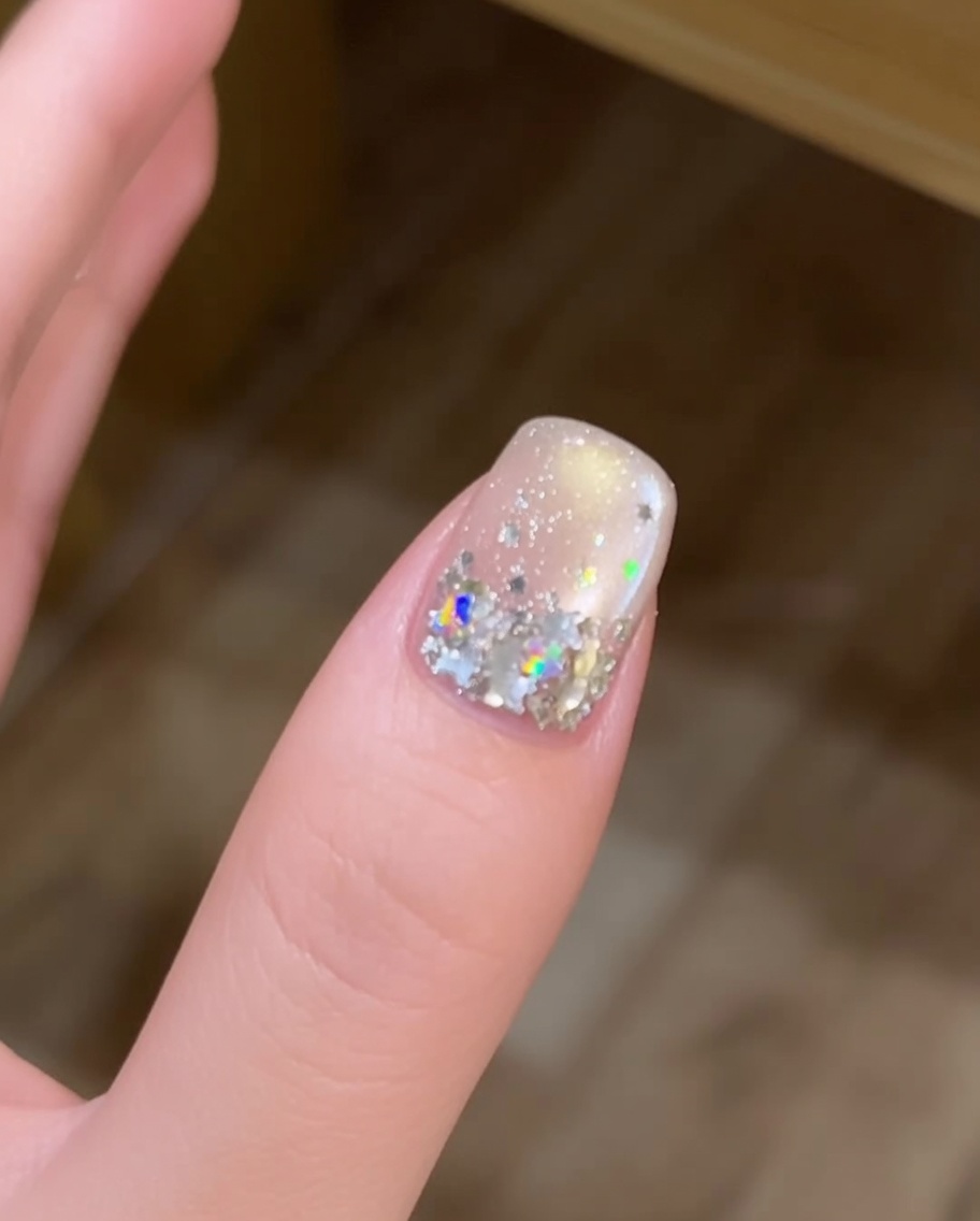 Ein langer Nagelpinsel trägt eine frische, abgerundete Perle aus klarem Aufbaugel in der Mitte eines Fingernagels auf.
