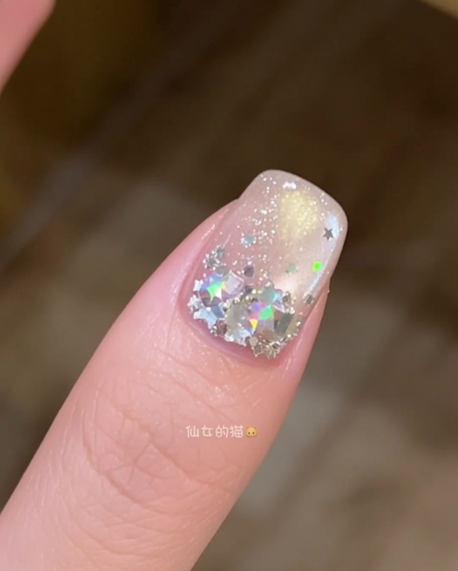 Nahaufnahme eines Nagelpinsels, der eine Schicht klares Aufbaugel auf einem mit Sternen verzierten Nagel glättet.