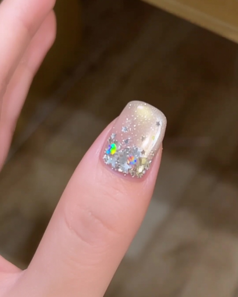Nahaufnahme einer Hand mit sternverzierten Nägeln, die in einer UV-Lampe aushärten.
