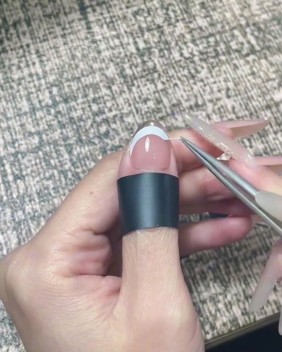 Eine Nagelfeile glättet sanft die freie Kante eines Nagels mit Chrom-Applikation.