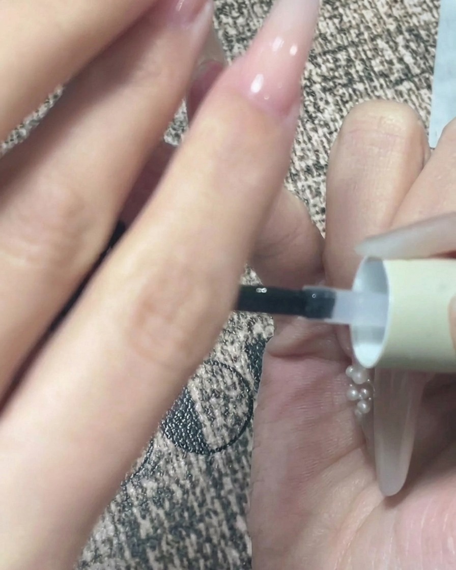 Nahaufnahme einer Hand, die nach dem Auftragen des Top Coats kurz umgedreht wird, damit sich das Gel selbst nivellieren kann.