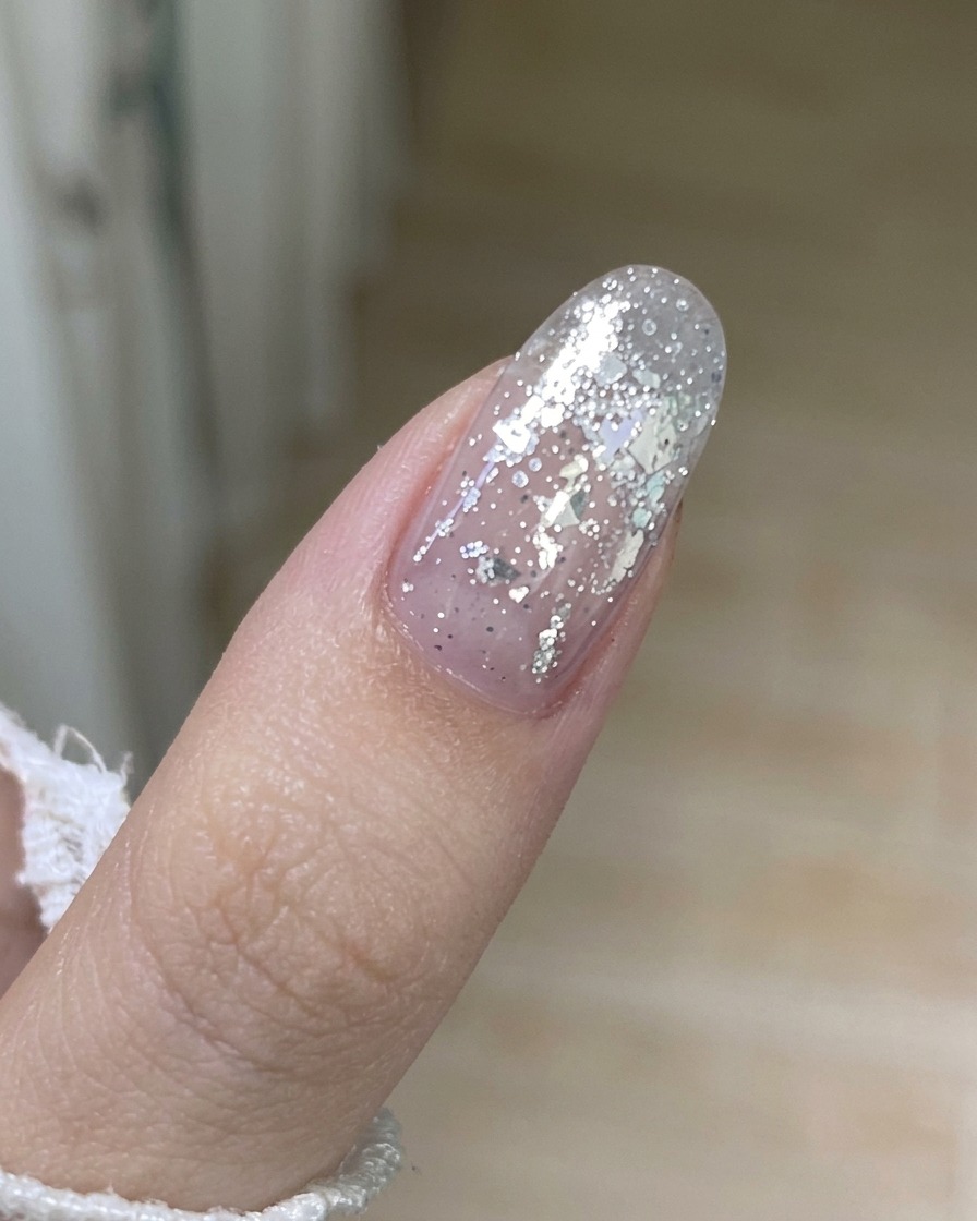 Nahaufnahme eines Metallwerkzeugs, das vorsichtig den Rand einer alten Gelschicht von einem Fingernagel anhebt.