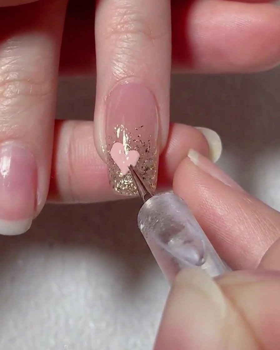 Ein Liner-Pinsel verbindet die pinken Gelpunkte zu einer Herzform auf dem Nagel.