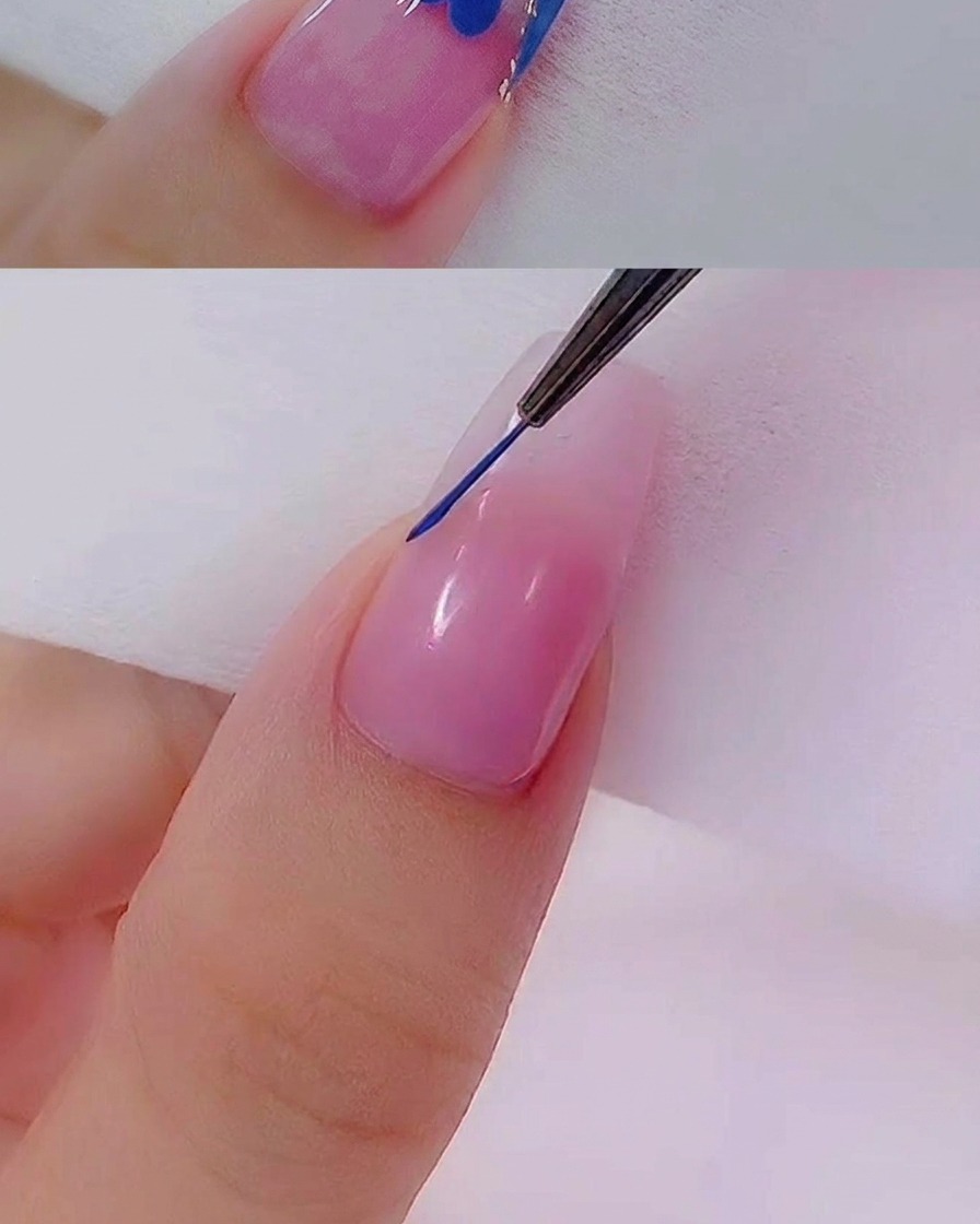 Nahaufnahme eines feinen Liner-Pinsels, der eine präzise blaue Linie über die Spitze eines natürlich aussehenden Nagels zieht.
