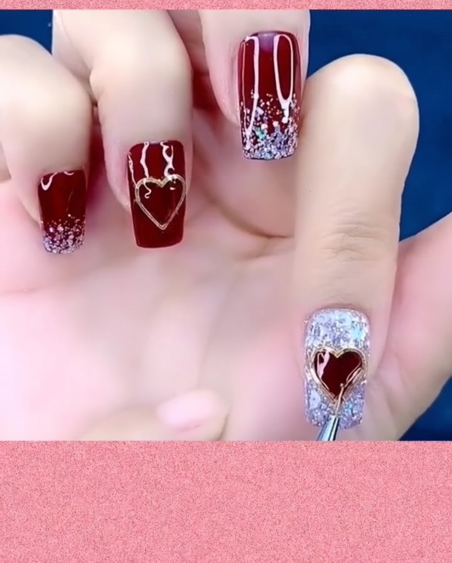 Ein Nail-Art-Pinsel trägt Top Coat um die Ränder eines Metall-Herz-Charms auf einem Nagel auf.