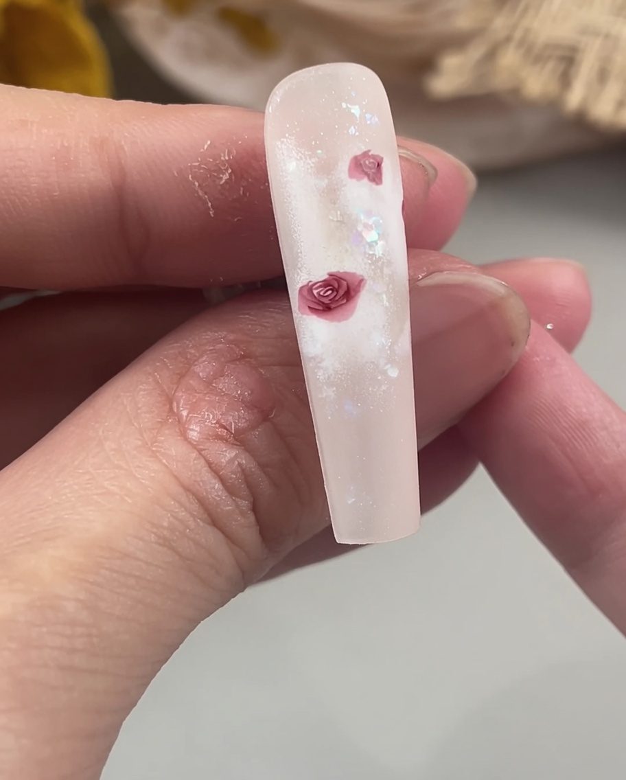 Ein Detailpinsel füllt die Zentren der Rosenblätter auf einem Nagel aus, um eine solide, definierte Blumenform zu schaffen.