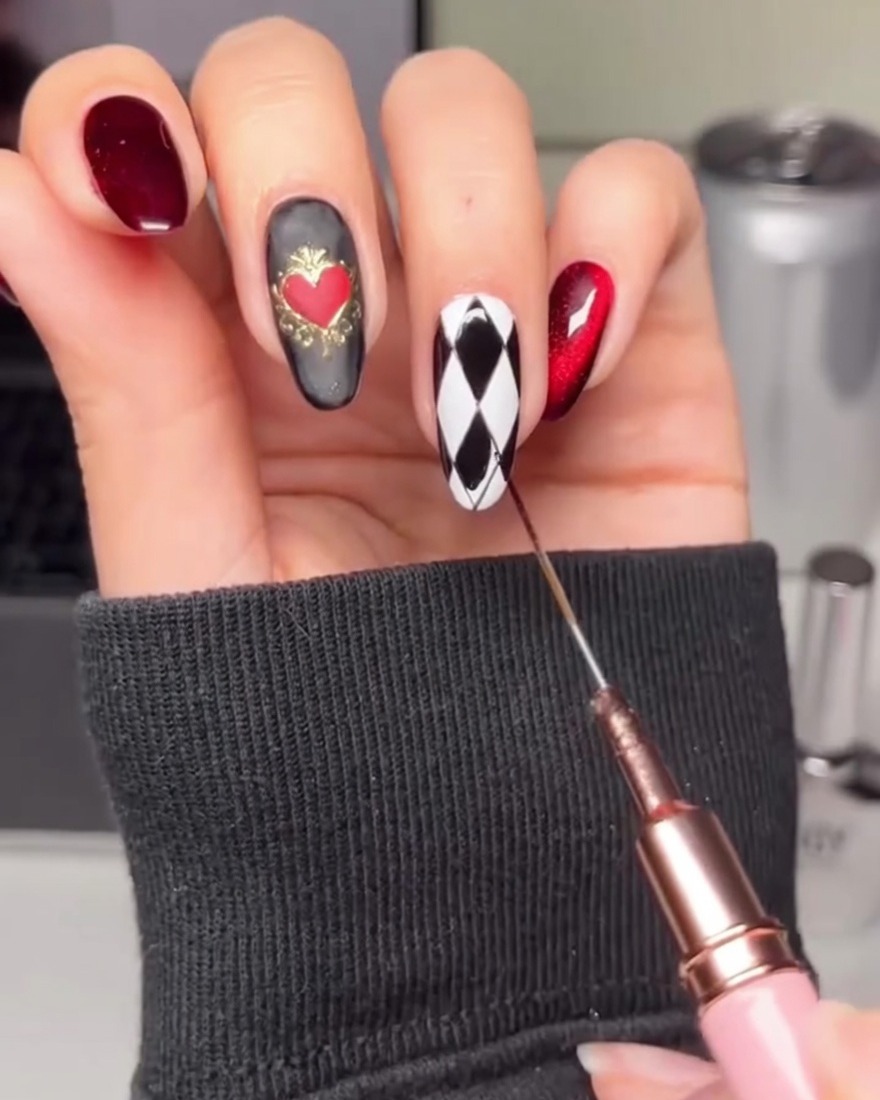 Ein Pinsel füllt abwechselnde Rauten auf dem weißen Nagel mit schwarzem Gel.